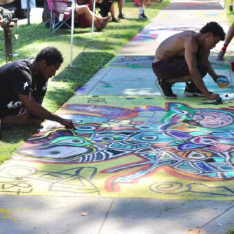 an image of two men making a chalk mural on the sidewalk together